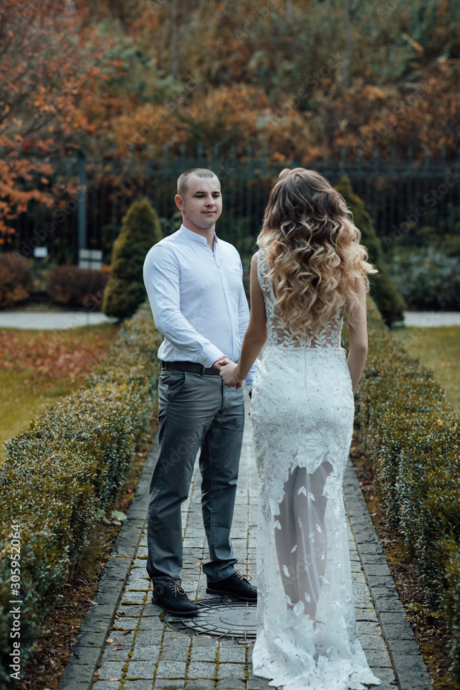 Fototapeta premium Man with girlfriend embracing her in a park. True love among lovers. Sincere emotions and love on the planet. Beautiful woman with make up and hairstyle. Young couple in love on a autumn day. 