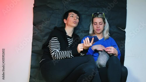 Lesbian couple taking selfie on smartphone with devon rex cat. photo