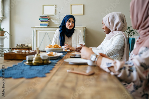 Canvastavla Three young muslim women drinking tea at the kitchen table - Arabian Millennials