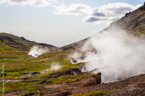 Geothermal hot springs steaming and smoking in the mountains, valley, foothill