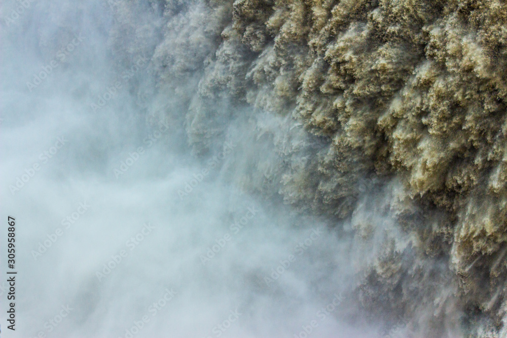 Big waterfall closeup splashing water drops forming mist and haze. Water detail  