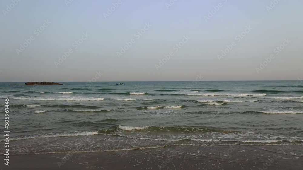 Aerial forward fly over sea wave crashing at the beach, small boat in the horizon, drone shot Aerial forward fly over sea wave crashing at the beach, small boat in the horizon, drone shot