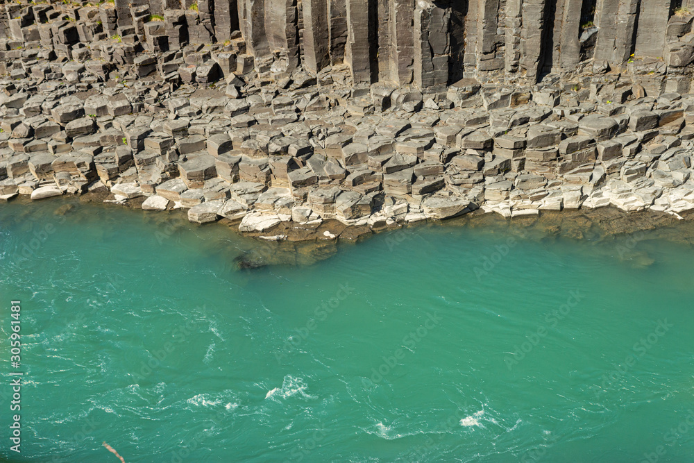 Clear turquoise, cyan water in river and basalalt rock columns, Studlagil Canyon Iceland canyon