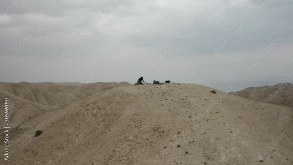 Aerial fly backwards from a single man sitting on a sand hill in the Israel desert, drone shot Aerial fly backwards from a single man sitting on a sand hill in the Israel desert, drone shot