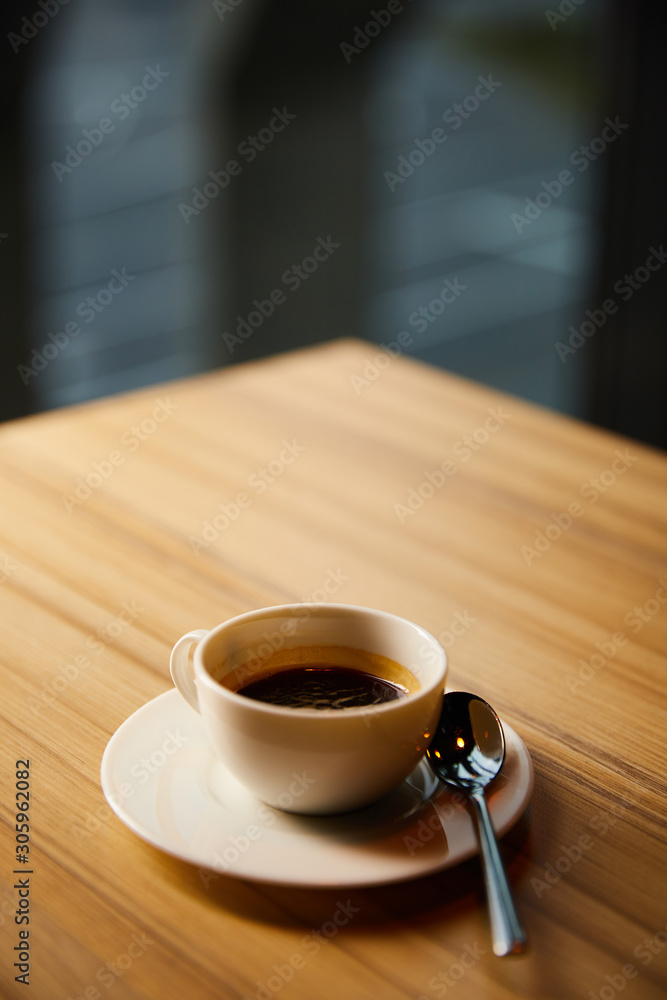 selective focus of white cup with coffee near spoon in cafe selective focus of white cup with coffee near spoon in cafe