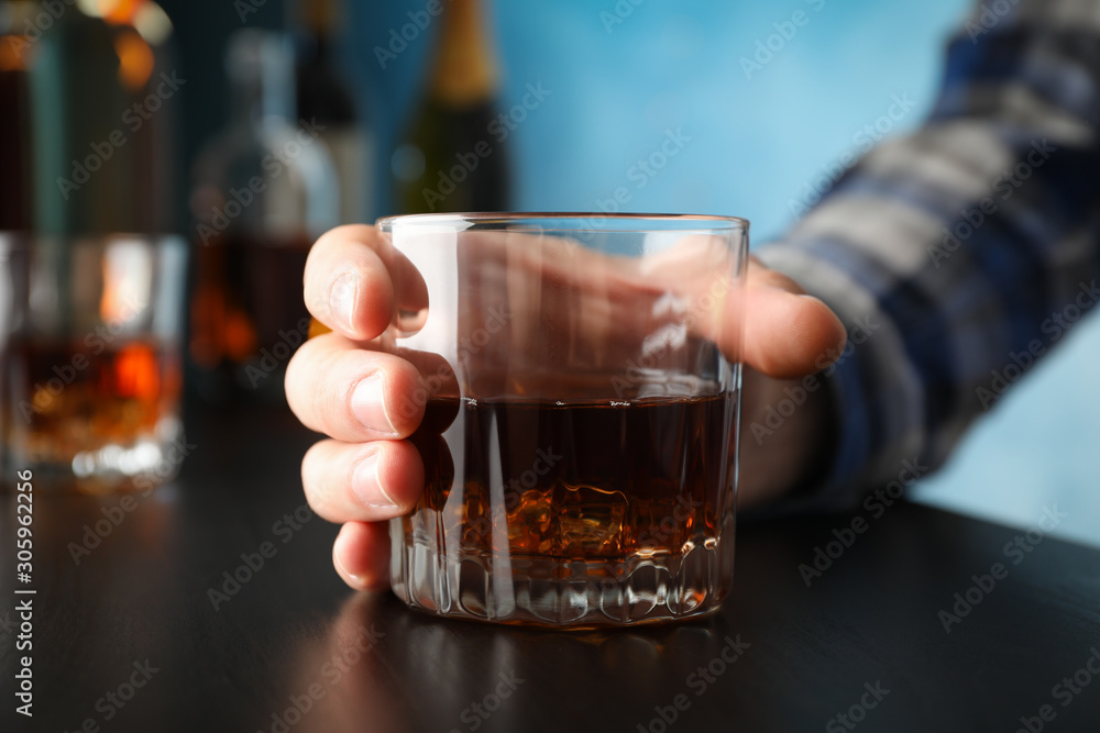 Male hand holds glass of whiskey on black table, close up Male hand holds glass of whiskey on black table, close up