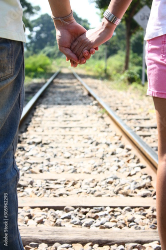 Rear View Of loving couple holding hands and walking together at railroad tracks for travel, love and Valentine's day concept