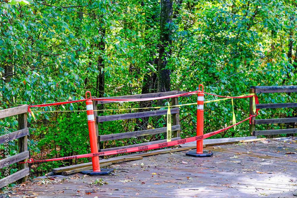 Warning Tape on Broken Railing of a Raised Wooden Walking Trail Warning Tape on Broken Railing of a Raised Wooden Walking Trail