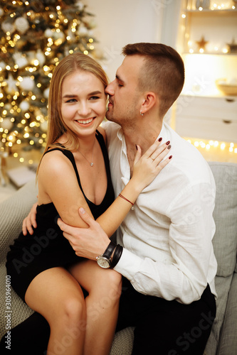 couple in love kisses and hugs on the sofa near the Christmas tree lights. New year's night. Christmas.