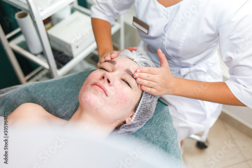 Doctor beautician makes cosmetic facial massage. Woman relaxes on a cosmetic chair