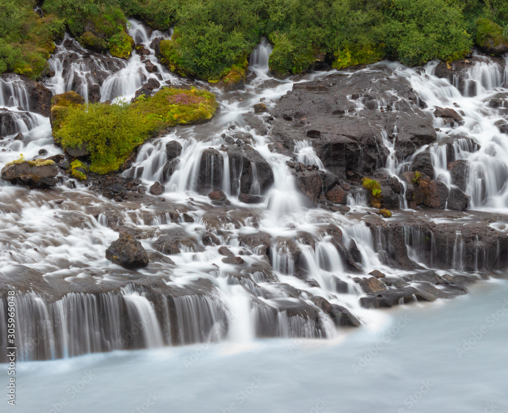 Waterfall in the forest, cascading water into a glacial river Waterfall in the forest, cascading water into a glacial river