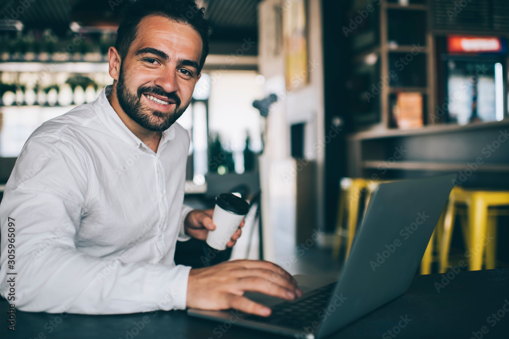 Portrait of happy male entrepreneur working remotely in public coffee shop with high speed internet connection, skilled successful man using laptop application for accounting online document Portrait of happy male entrepreneur working remotely in public coffee shop with high speed internet connection, skilled successful man using laptop application for accounting online document