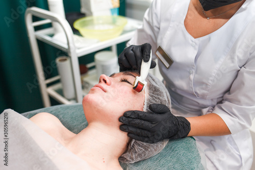 Photos Doctor cosmetologist makes facial massage procedure using a dermo roller
