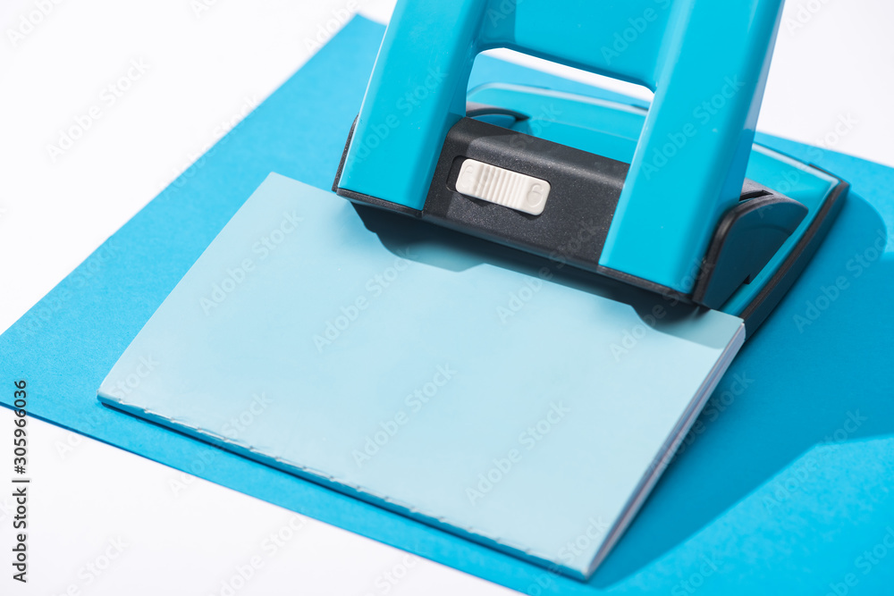high angle view of notebook, holepunch and paper isolated on white high angle view of notebook, holepunch and paper isolated on white