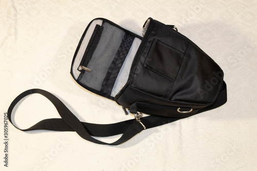 Close-up. On a white background a black bag with a strap for the camera.
