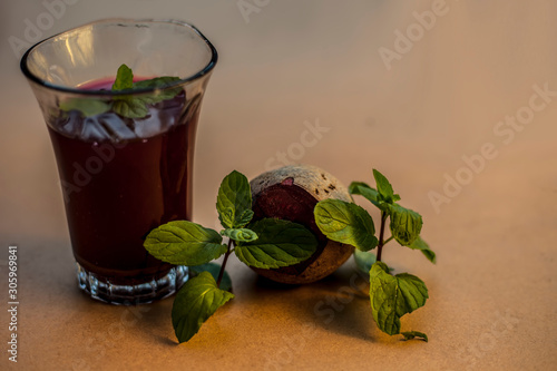 High angle shot of fresh beetroot juice in a glass on the brown surface along with some freshly sliced beetroot vegetable with it.Horizontal high angle shot. photo