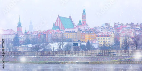 Panorama of Royal Castle and colorful houses by the Vistula River in the snowy evening, Warsaw, Poland.