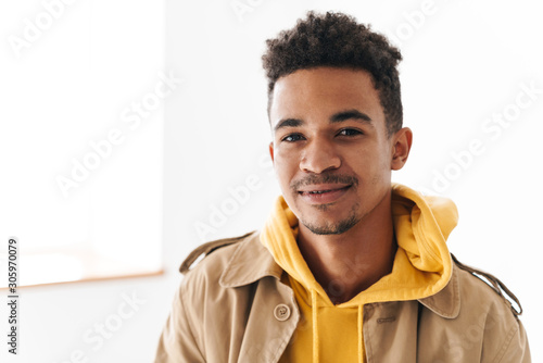 Photo of pleased african american man smiling and looking at camera