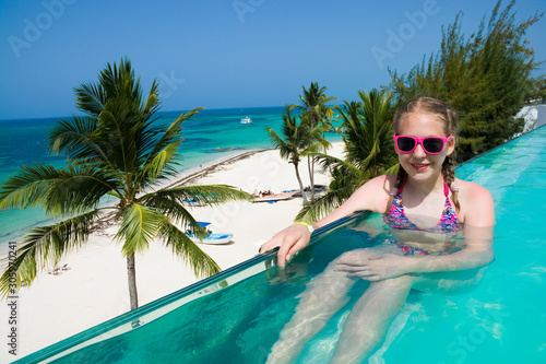 Caucasian teenage girl relaxing in infinity swimming pool in luxury hotel, Punta Cana, Dominican Republic. Summer vacation concept