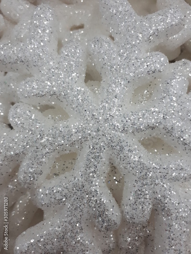 close-up of a white shiny vibrant snowflake on a gray concrete wall background