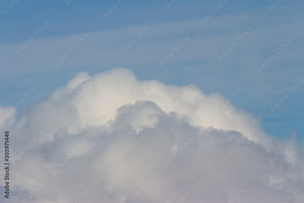 Two white fluffy clouds, above the clouds, blue sky Two white fluffy clouds, above the clouds, blue sky