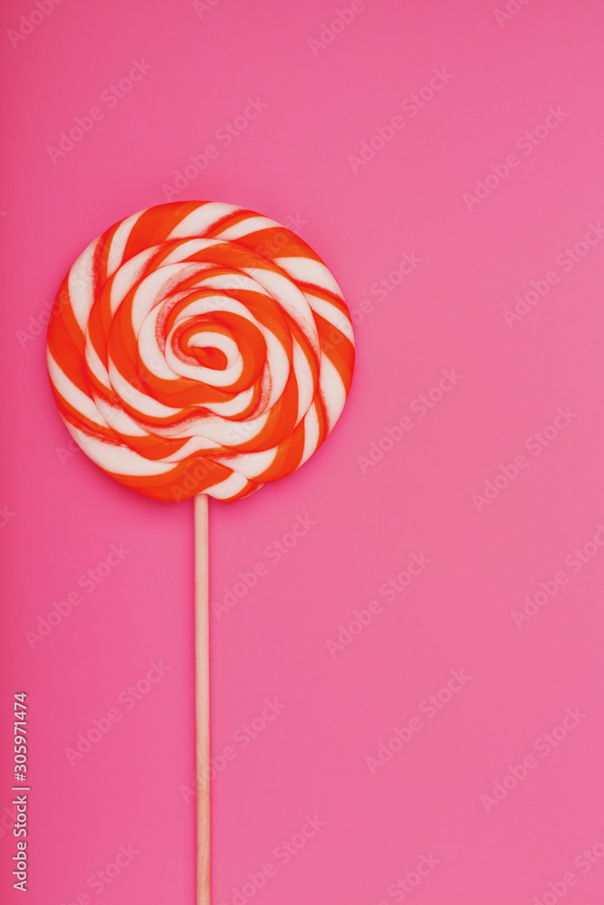Orange Lollipop on a pink background with a soft contrast. Minimal concept with copy space.