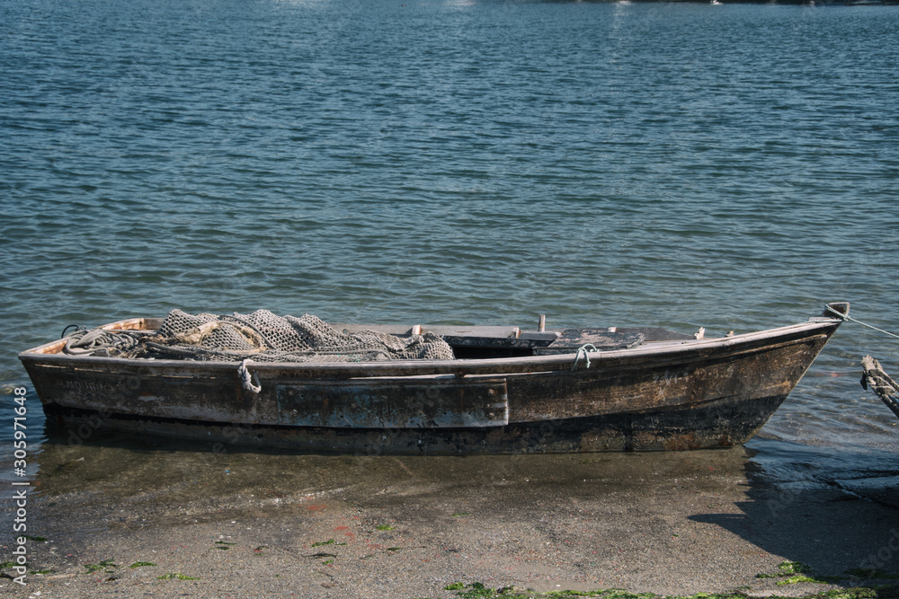 Fototapeta Old wooden rowboat with fishing net in port.
