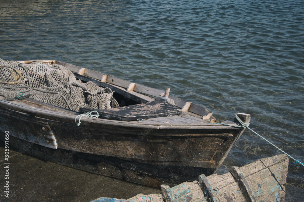 Fototapeta Old wooden rowboat with fishing net in port.