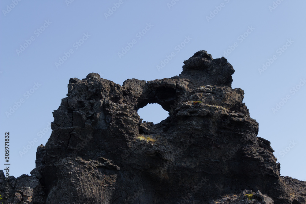 Hole in a lava monument, opening in big black basalt mountain