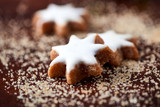 Christmas cookies (cinnamon stars) and brown sugar on dark background. Close up. 