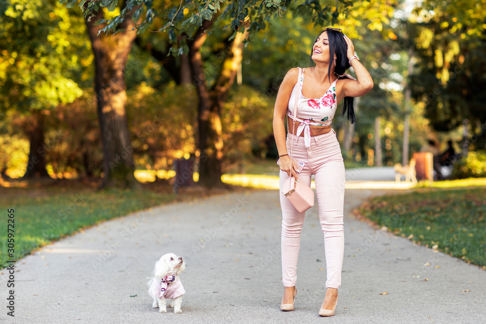 Fototapeta premium Fashion girl in park in pink with her small dog