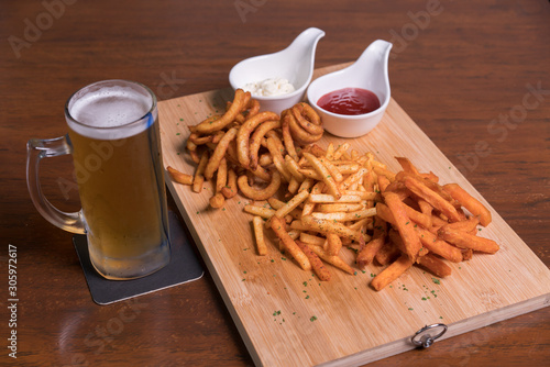 Restaurant food. Wooden board with lot french fries with two dipping sauce served with beer. 