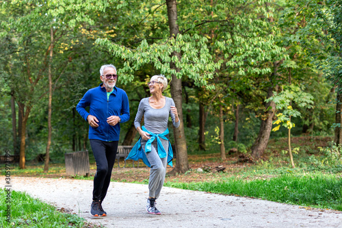 Fototapeta Naklejka Na Ścianę i Meble -  Mature couple man and woman jogging in the park