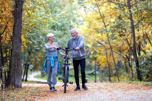 Mature couple woman and man with bicycle walking in the park and talk © pucko_ns