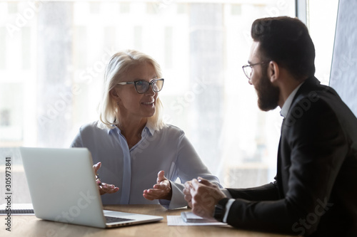 Middle-aged businesswoman discuss idea with male colleague at meeting