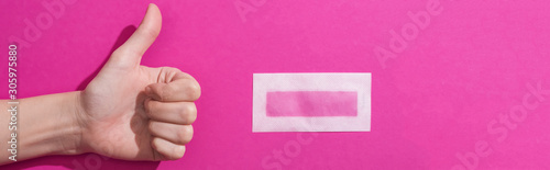 cropped view of woman showing thumb up near depilation wax stripe on pink background, panoramic shot