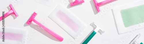 top view of green and pink razors and depilation wax stripes on white background, panoramic shot