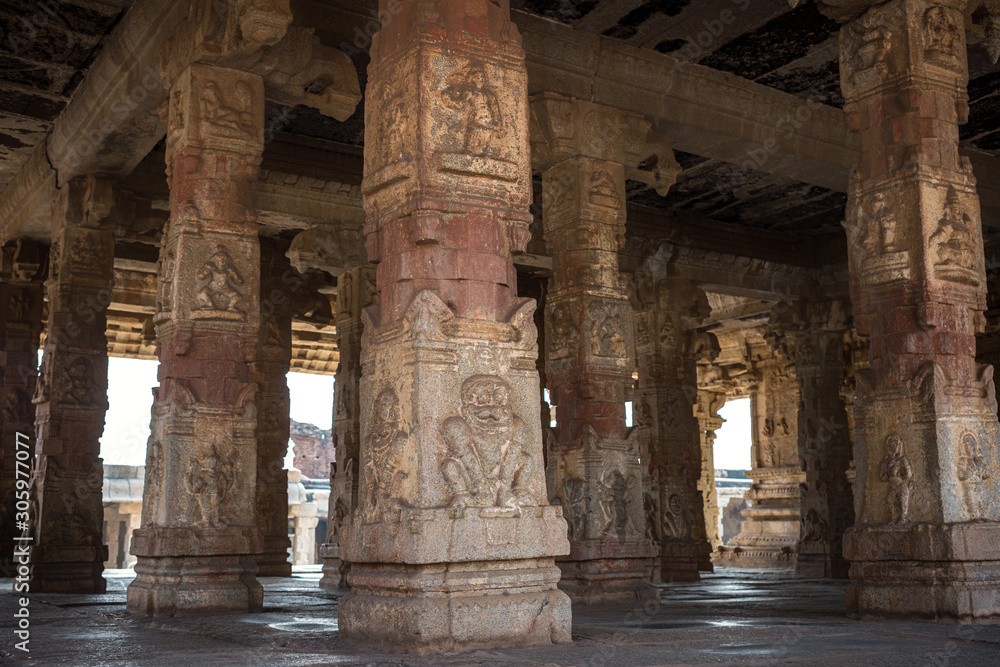 Carved stone columns in an ancient temple. The ruin of ancient temples near the village of Hampi. Krishna Temple. India