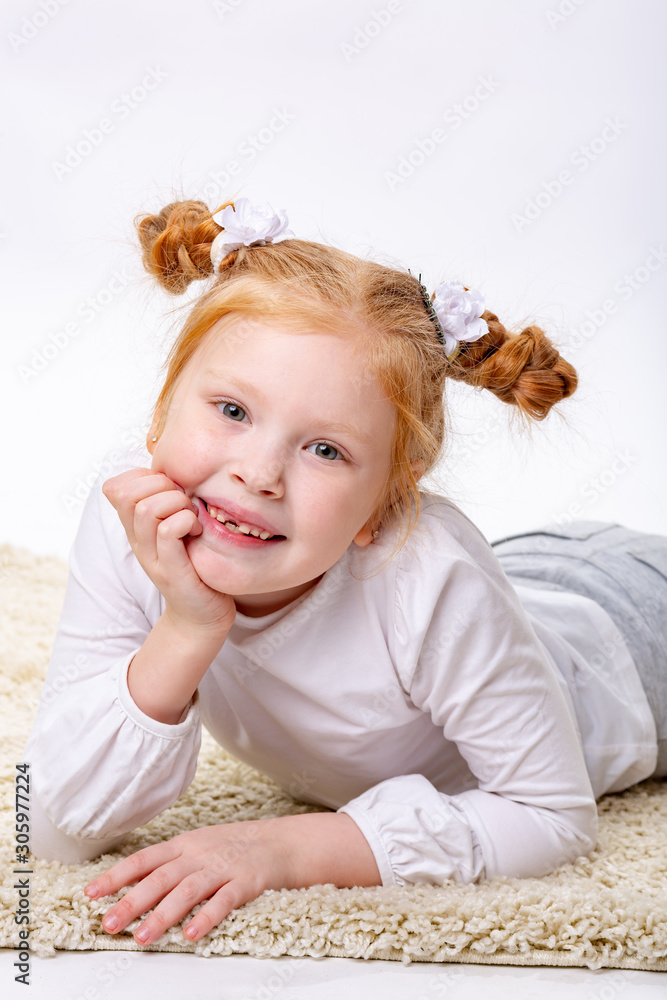 Fototapeta premium The little red haired girl is leaning her face on her hand