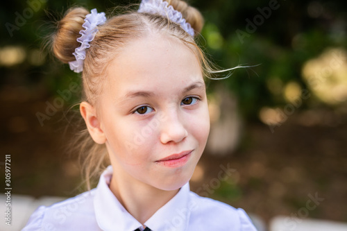 Foto A schoolgirl in a white blouse with a red tie, with a bow in the class