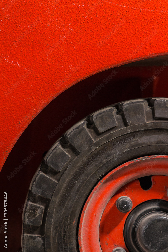 Red dirty forklift wheel in a factory with dirty tyres and dirty nuts and bolts. Vivid bright colours and dirty tyres. Covered in dust and grime Red dirty forklift wheel in a factory with dirty tyres and dirty nuts and bolts. Vivid bright colours and dirty tyres. Covered in dust and grime