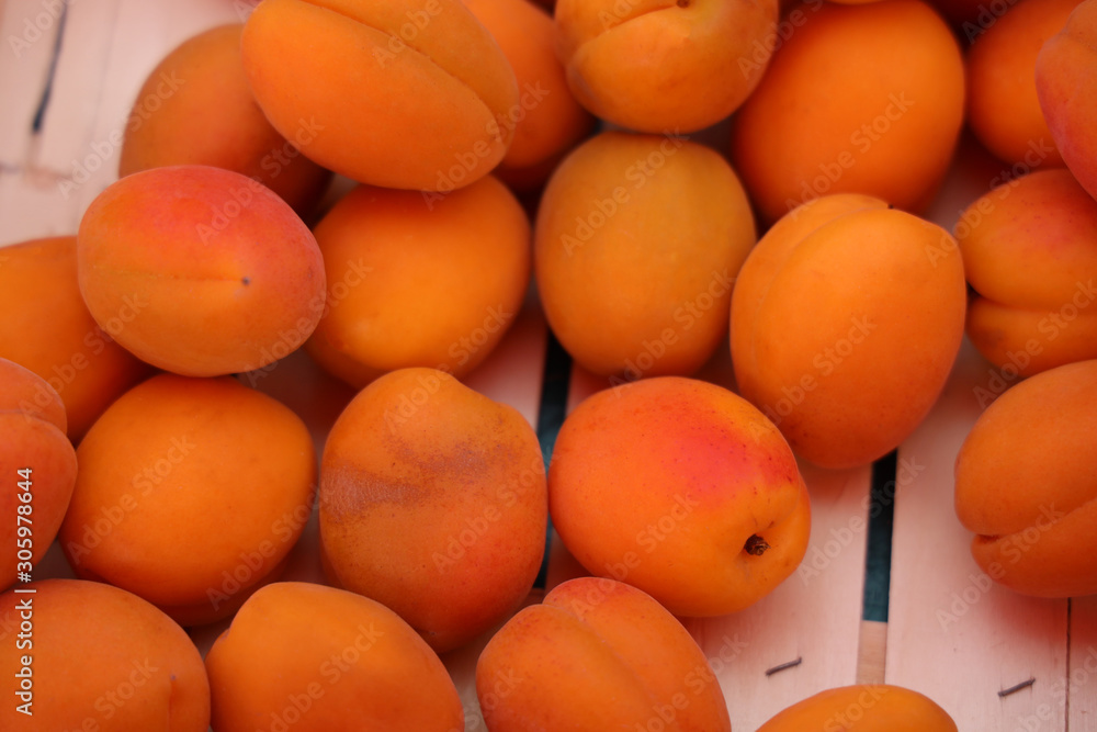 Apricots in a wooden crate at a farmers market.