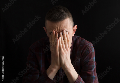 Depressed man on a black background. The concept of fatigue, grief, problems.