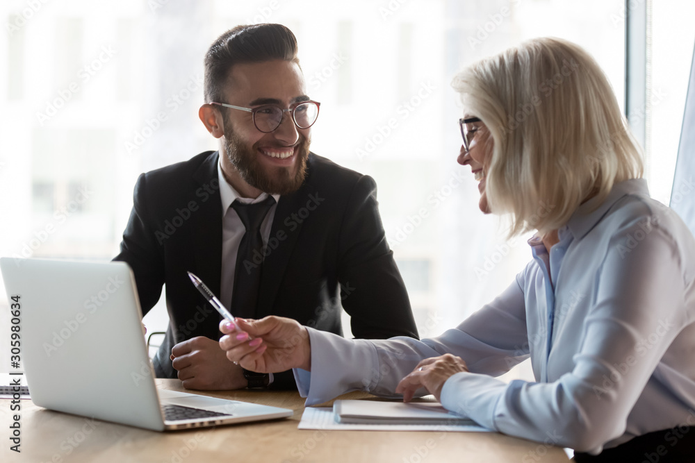 Smiling diverse businesspeople talk discussing ideas on laptop Smiling diverse businesspeople talk discussing ideas on laptop