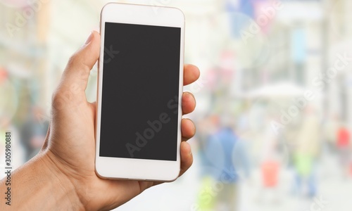 Hand holding smartphone on blurred city background
