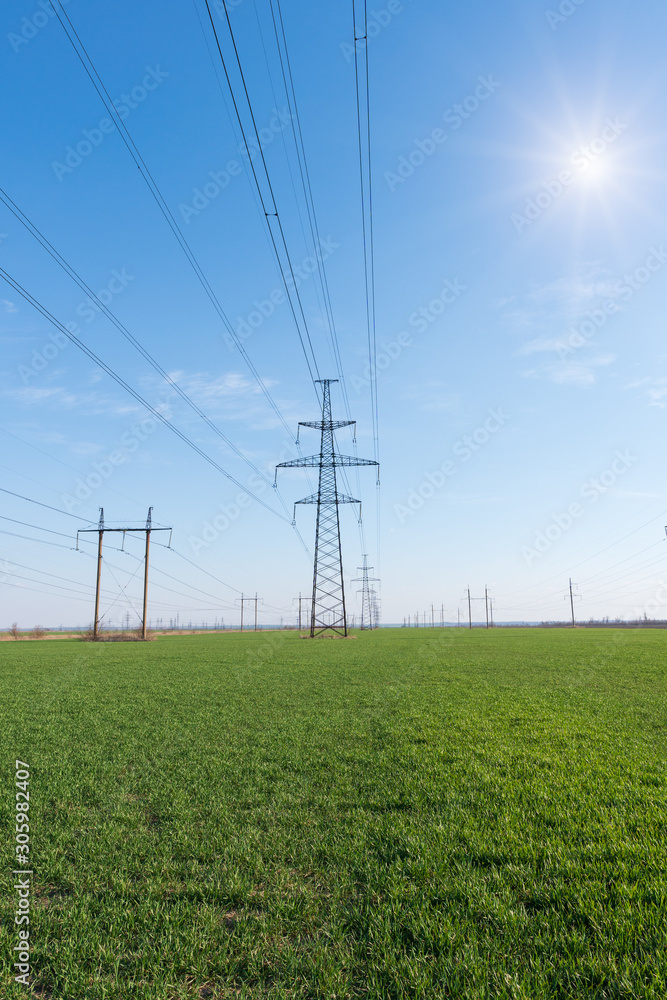 Electrical net of poles on a panorama of blue sky and green meadow Electrical net of poles on a panorama of blue sky and green meadow