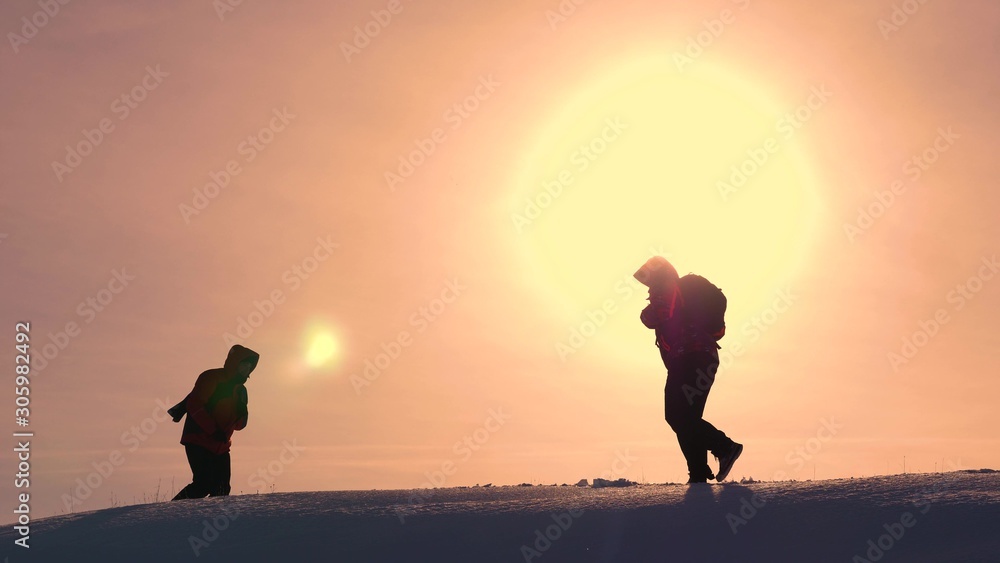 Teamwork concept and winning business. Travelers meet on a snowy hill and rejoice at the victory against the backdrop of beautiful yellow sun. teamwork of people in difficult conditions.