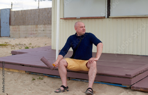 man on a painted porch with a roller in his hand photo