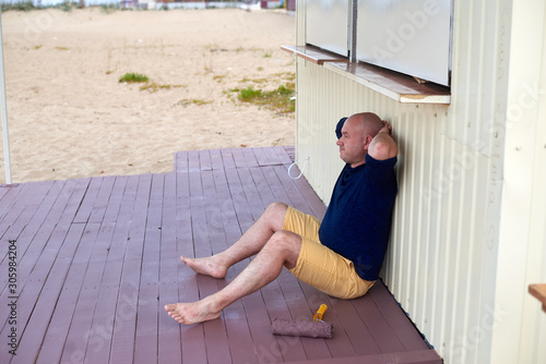 man on a painted porch with a roller in his hand photo