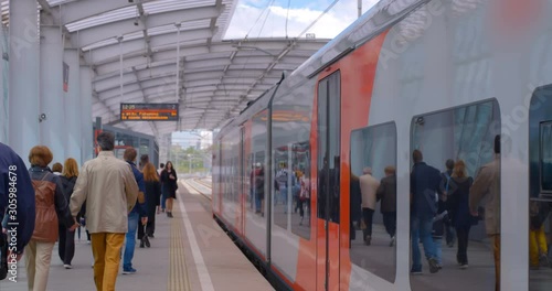 Passengers got out the train and walk along the platform of the ground metro station, the train still stands on the platform